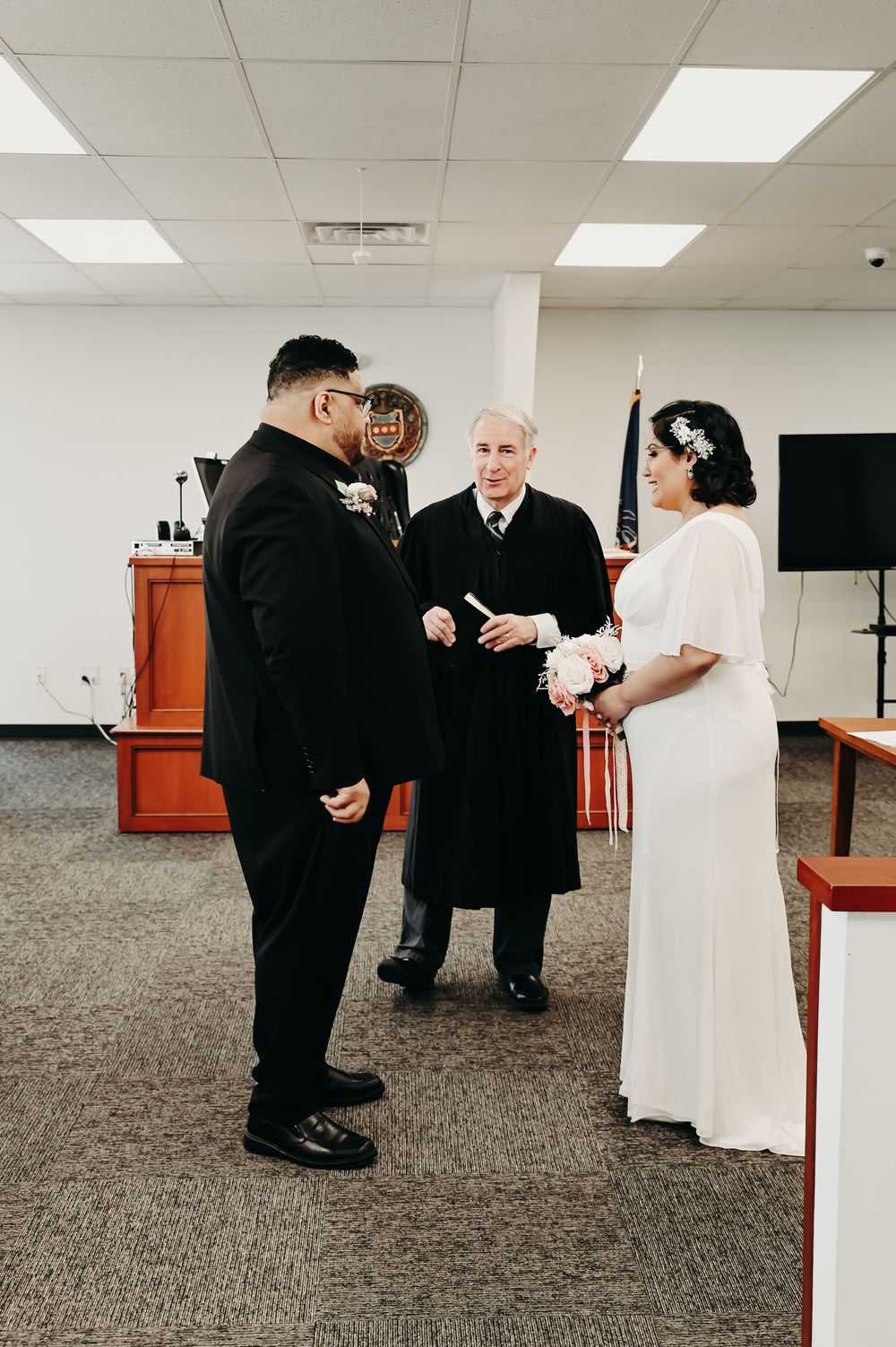 Wedding ceremony preparations in a carpeted room with officiant and couple.