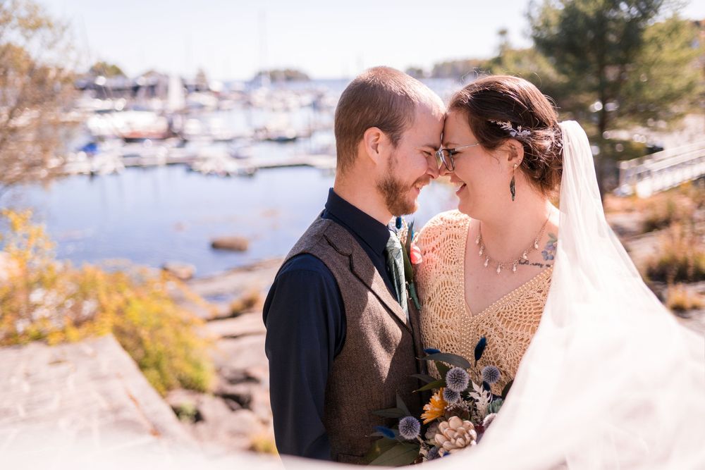 A couple shares romantic moments during their coastal wedding celebration at sunset by the water.