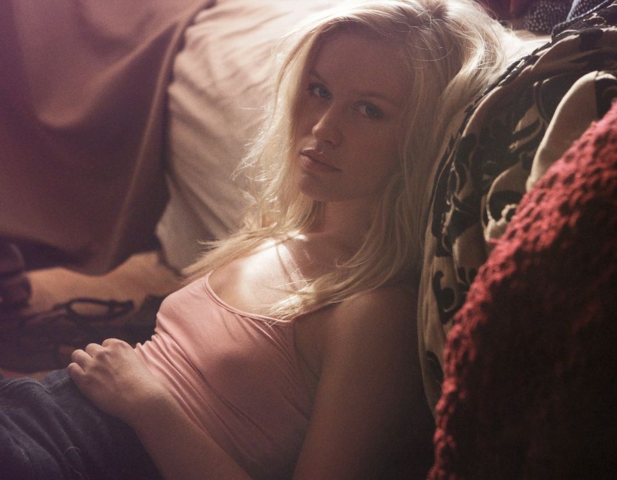 Intimate indoor portrait with soft lighting and pink clothing against dark background.