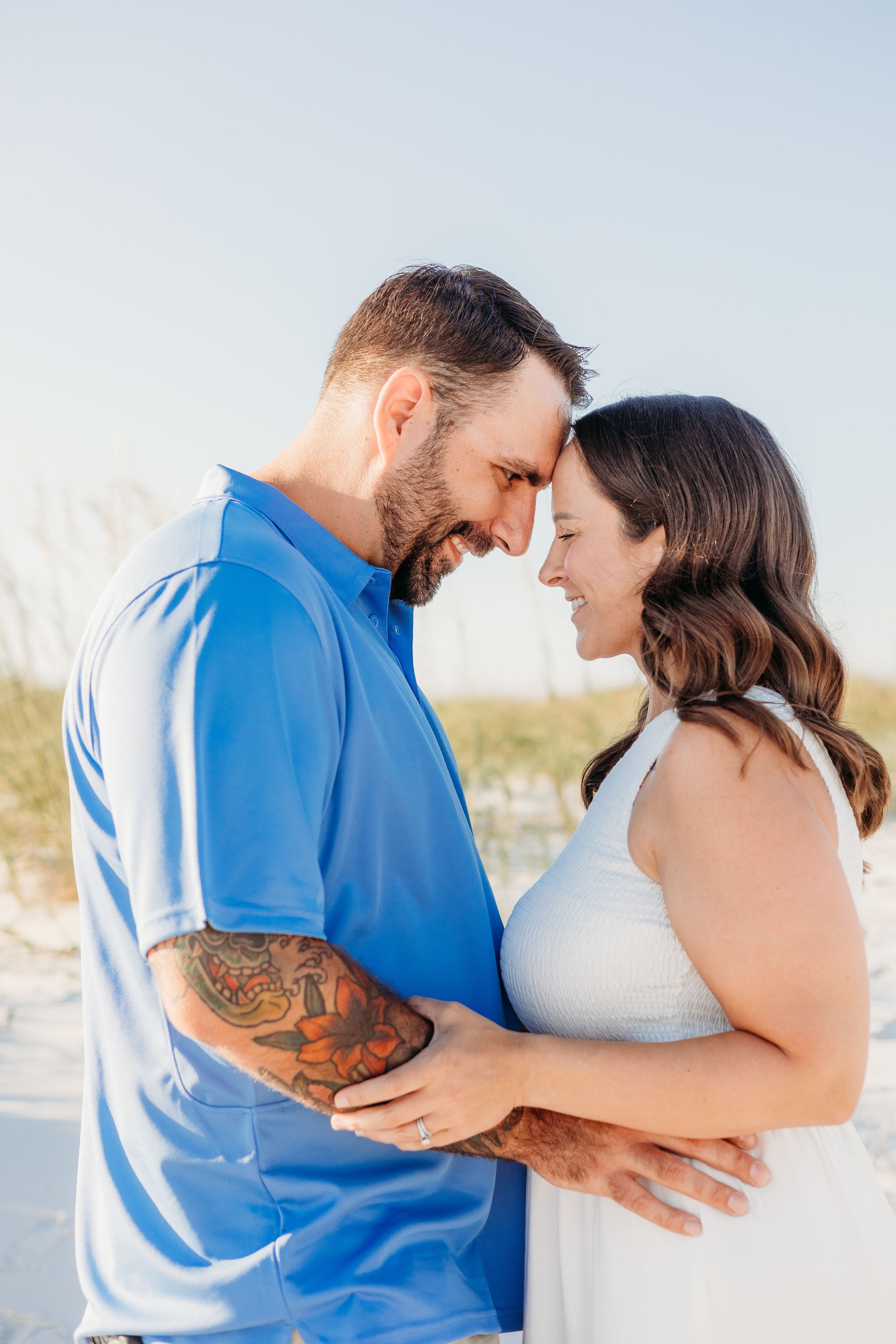 Romantic couple in blue and white embracing on a sunny beach.