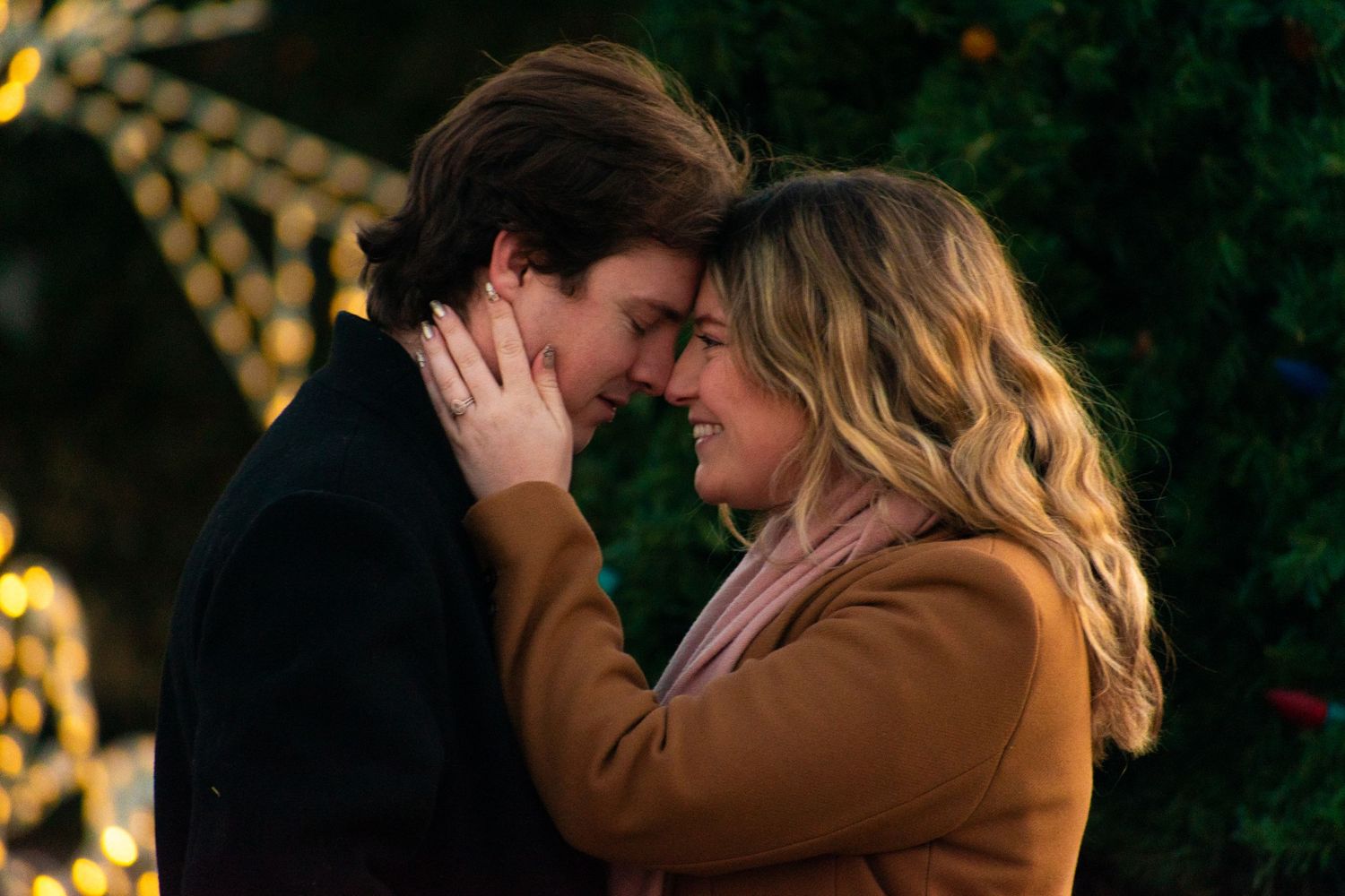 An intimate moment captured against a backdrop of twinkling Christmas lights and decorations.
