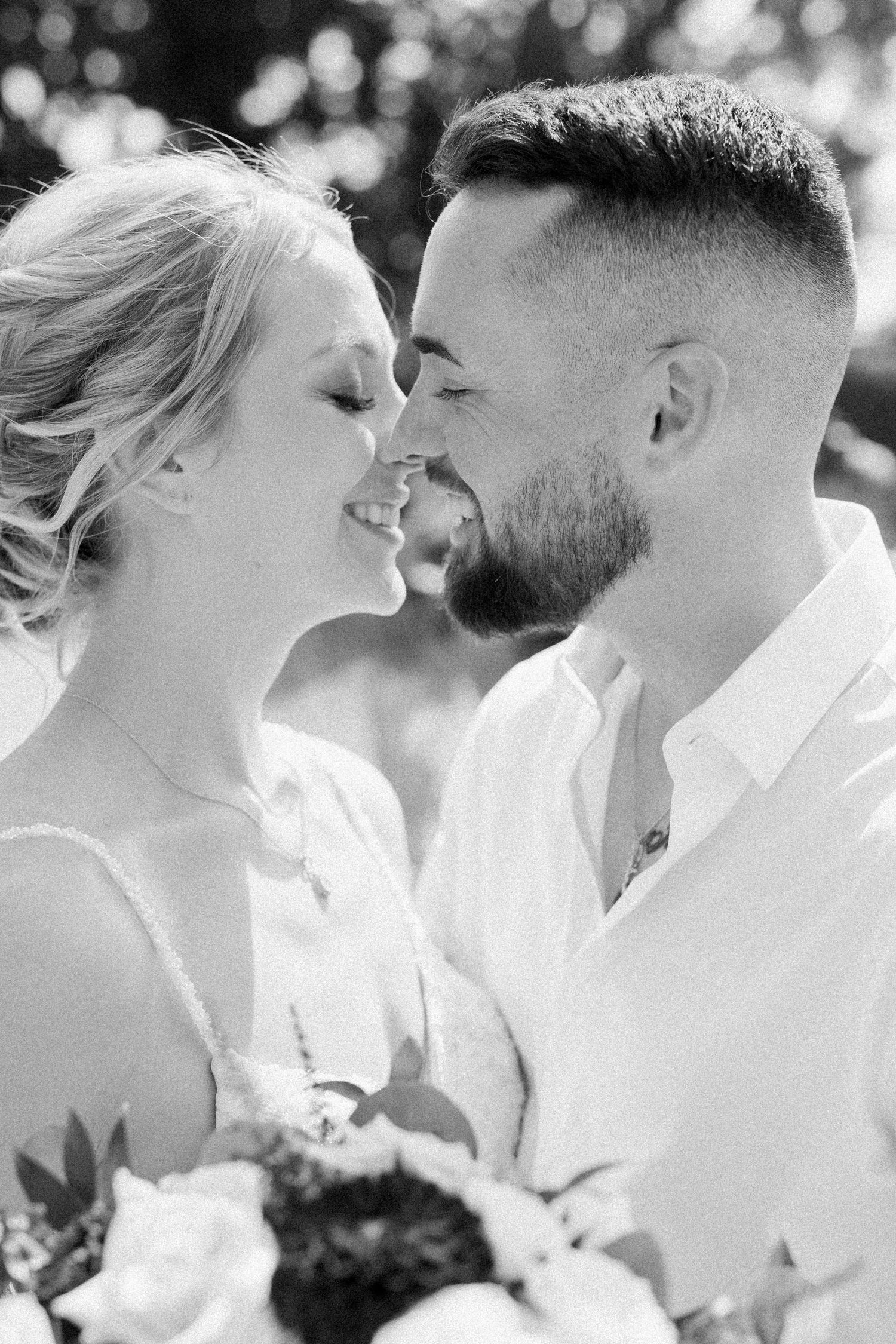 A close photo as a couple leans in for a kiss, smiling brightly. Photo by Katie Crane