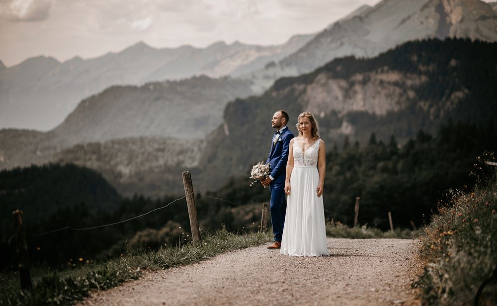 Bride and groom standing on a mountain path surrounded by stunning Alpine scenery on their wedding day.