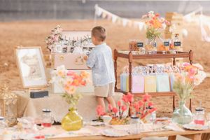 Outdoor party setup with pastel decorations and floral arrangements on rustic tables.