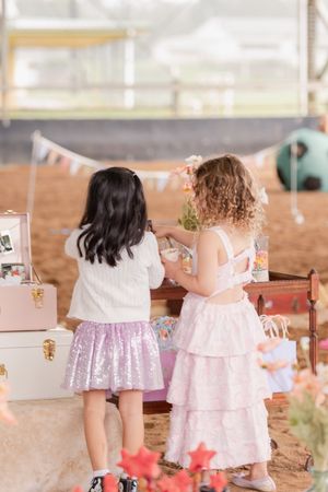 Small children in pink and white dresses playing at a party venue.