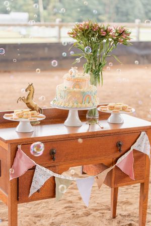 Rustic wooden tables decorated with pastel bunting flags and floral centerpieces for a garden party.