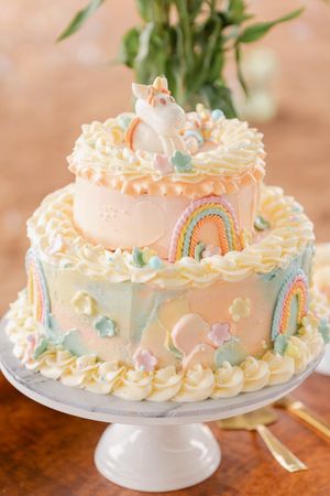 Pastel decorated birthday cake with delicate piping and soft colors on a white cake stand.
