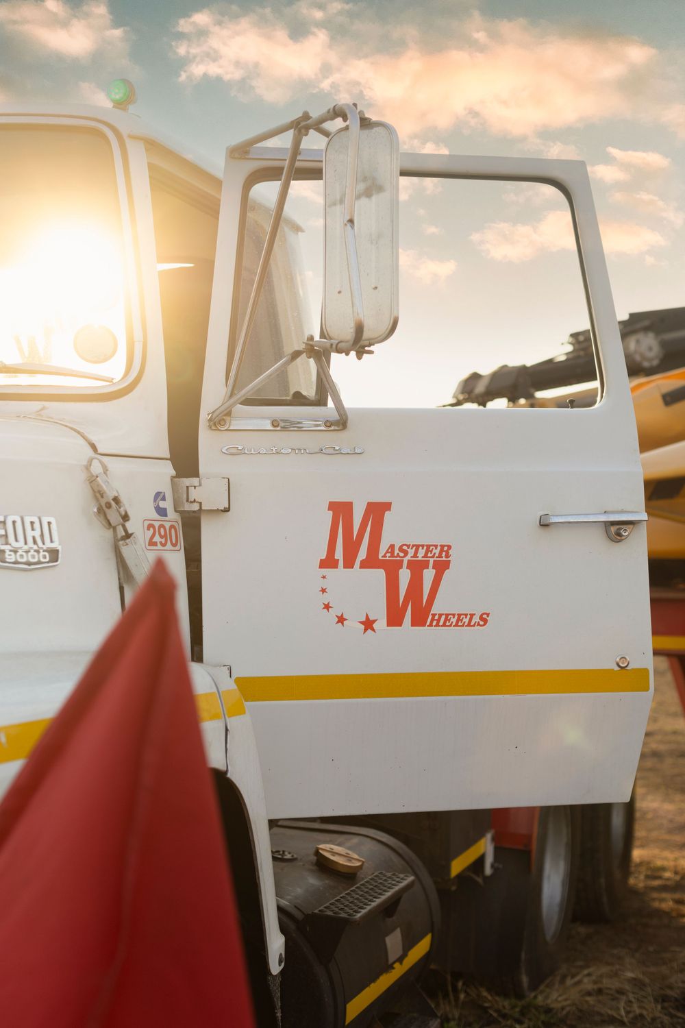 Master Wheels branded white Bedford truck cab in golden sunset light.