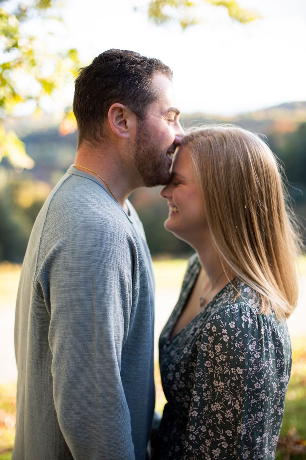 A tender moment between a couple standing close together in an outdoor setting.