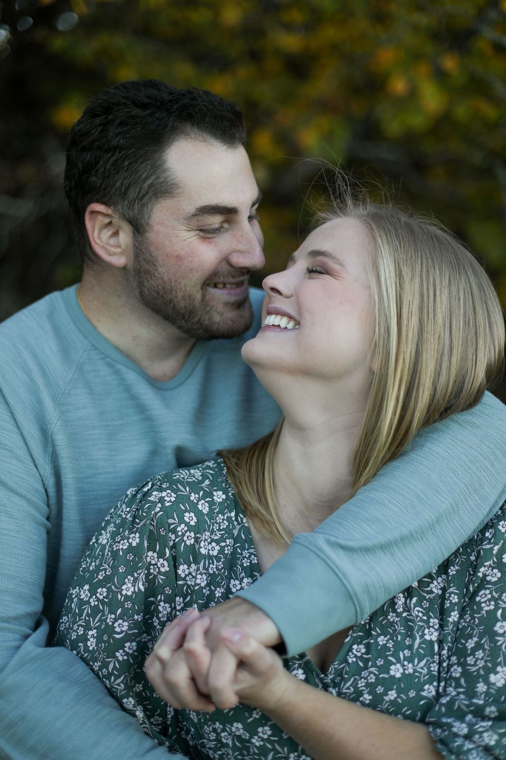 A couple shares a loving embrace while laughing together outdoors.