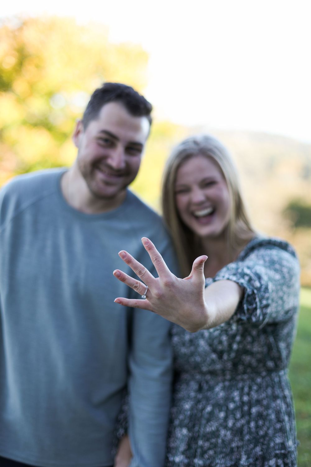 An excited couple shows off an engagement ring during their announcement photoshoot.