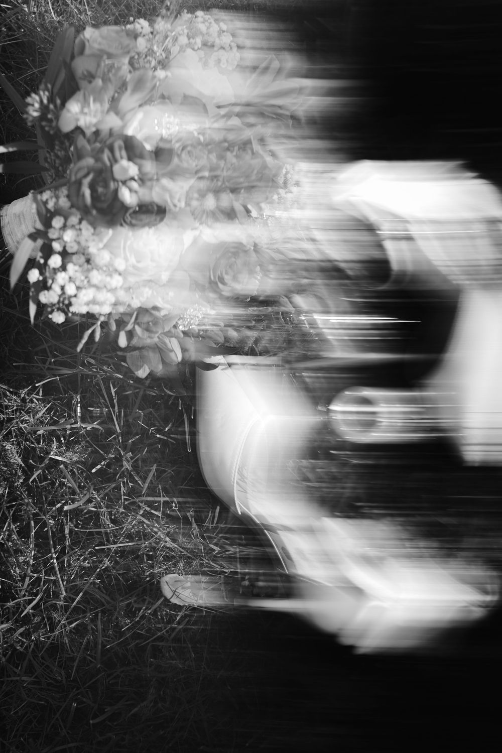 Blurred black and white photo of a vintage car with floral decorations at night.