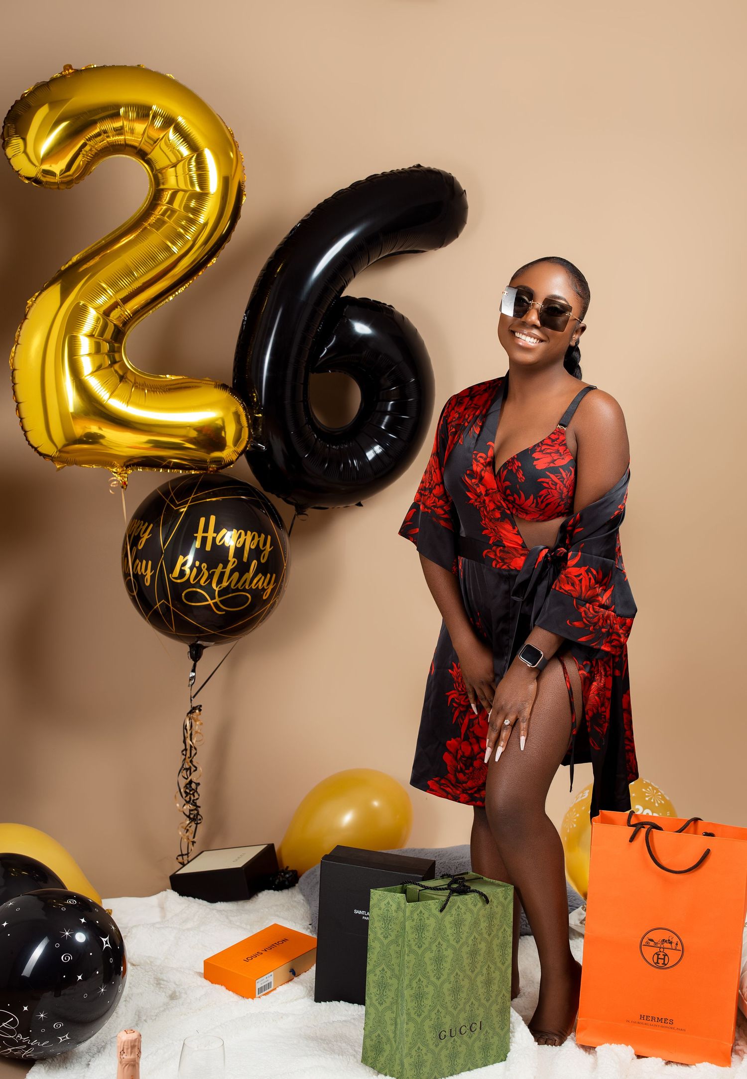 Birthday celebration setup with large number 26 balloons and designer shopping bags.