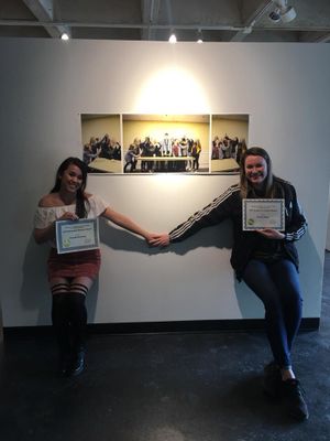 Multiple playful poses next to framed artwork hanging on a gallery wall.