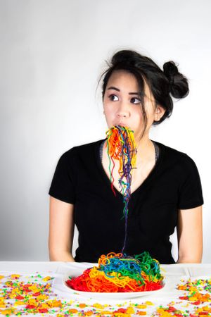 Creative food photography with colorful rainbow spaghetti against a white background.