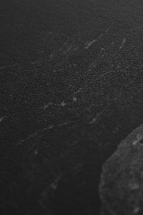 Close-up texture of dark scratched surface showing subtle marks and grains.
