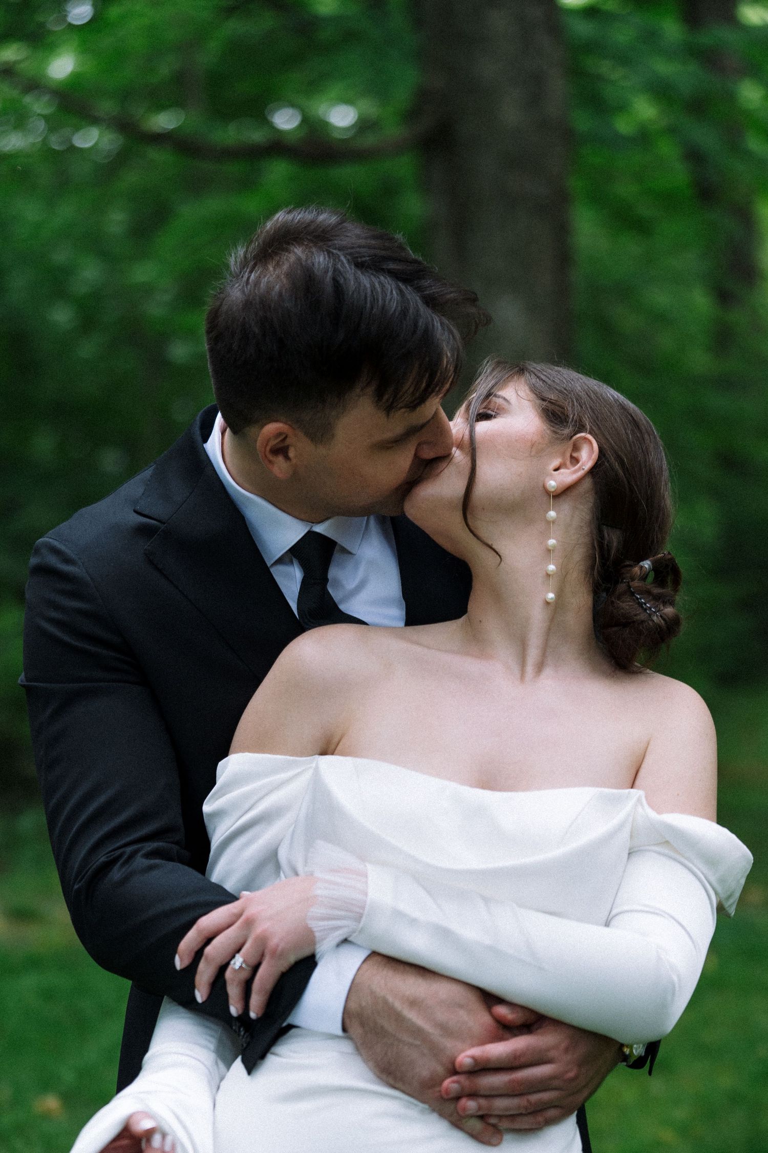 A romantic wedding kiss captured in a dreamy forest setting.