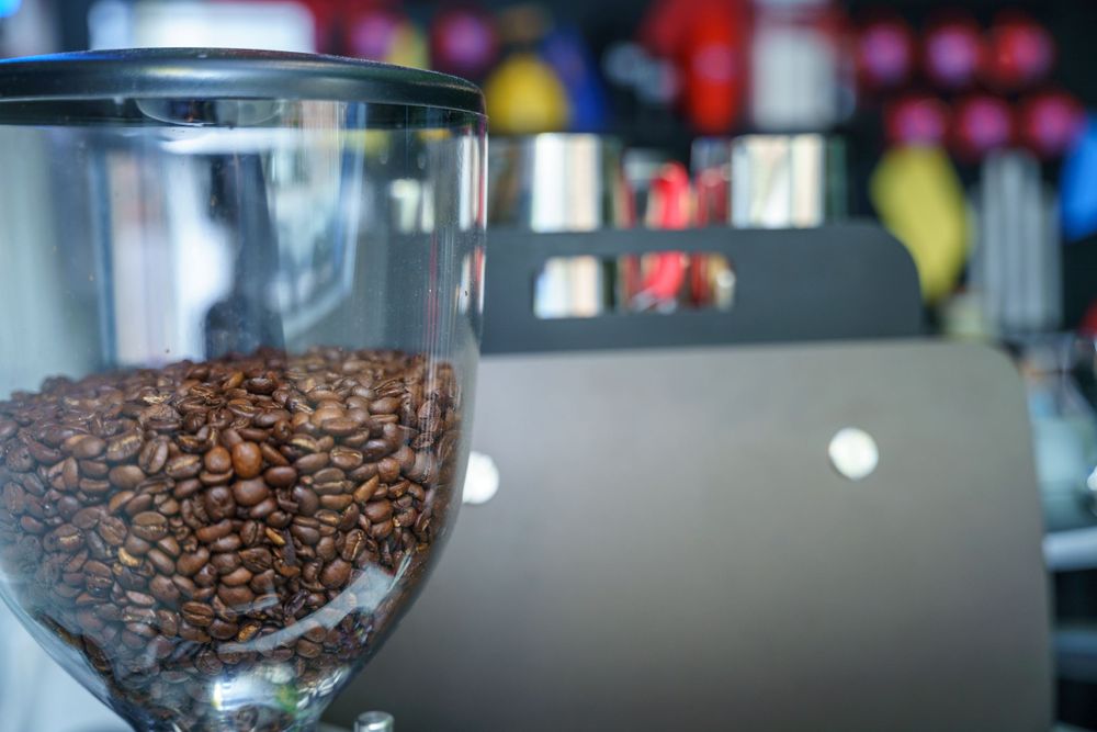 Coffee beans in a glass container with blurred background.