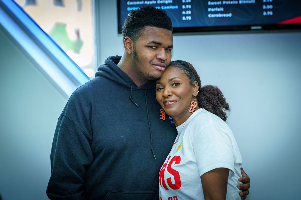 Two people embracing at a coffee shop counter.