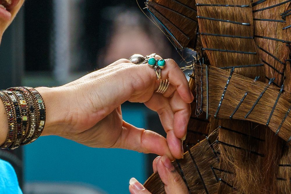 Hand wearing stacked bracelets and turquoise ring reaches toward wooden texture.
