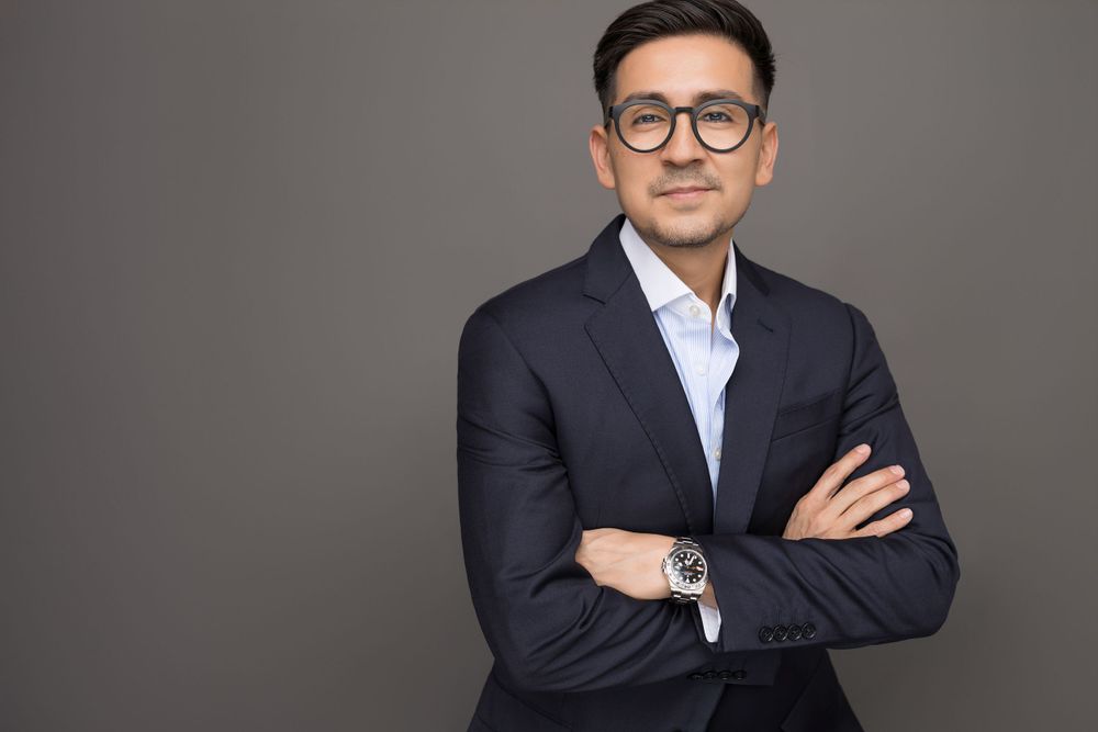 Professional studio shot of businessman in dark suit with crossed arms.