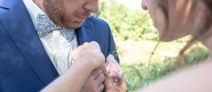 Une femme attache une rose sur la veste de son mari. gros plan mariage. Flashnoah photographie