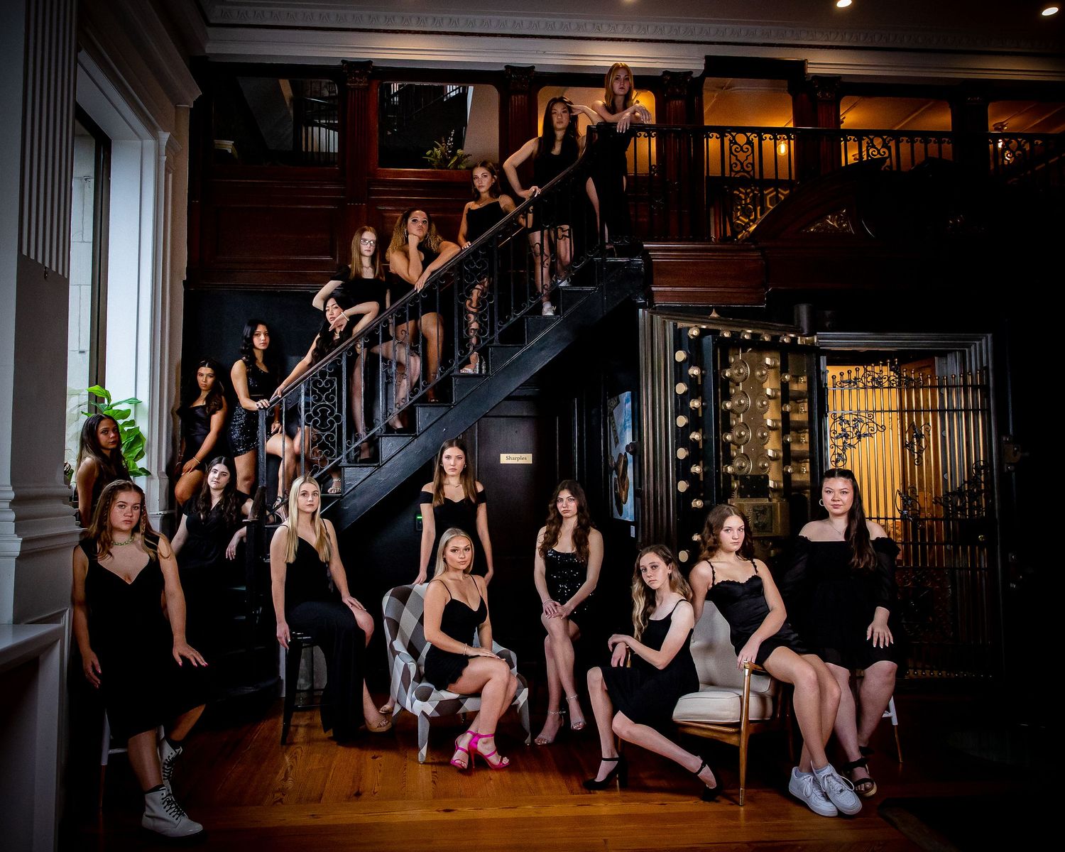 Dramatic team photo staged on elegant staircase in black formal attire.