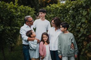 Casual family portrait session among green vineyard rows during golden hour.