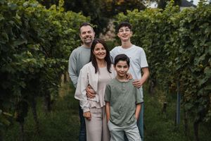 Family gathering in a vineyard with lush green grapevines in the background.