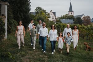 Extended family portrait session on a grassy hillside with church and village in background.