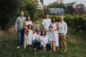 Multi-generational family photo shoot in a scenic countryside setting with church in distance.