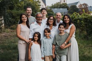 Family group poses together outdoors in coordinated casual outfits during golden hour photo session.