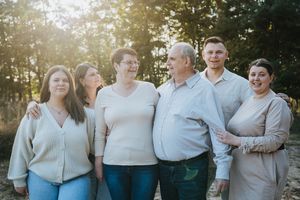 Casual group photo session with neutral colored outfits against natural outdoor backdrop.