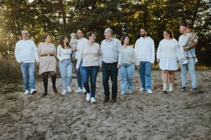 Group stands in line showing casual denim and neutral colored outfits during outdoor photo session.