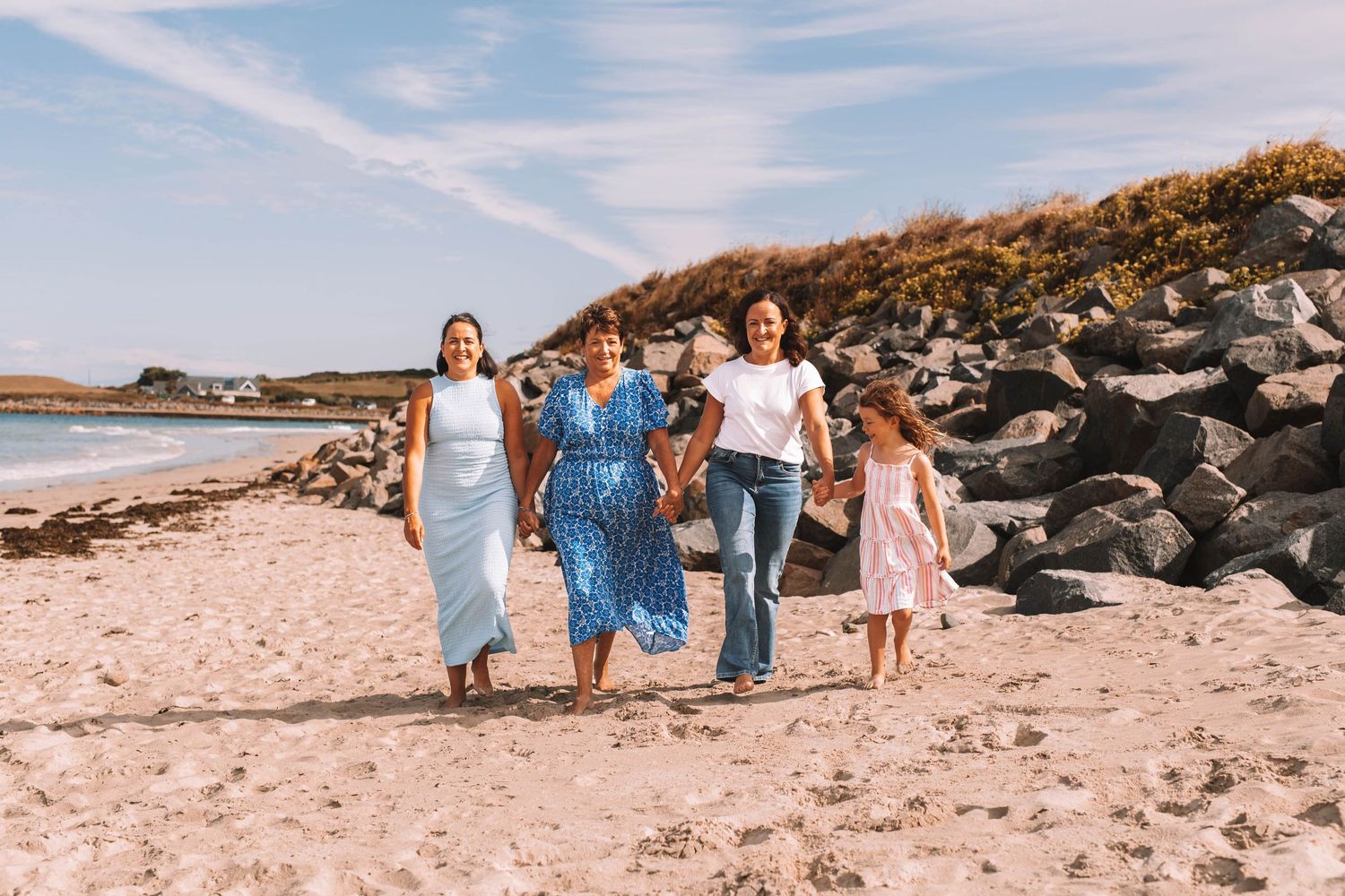 People walking together along a scenic rocky beach shoreline on a sunny summer day.