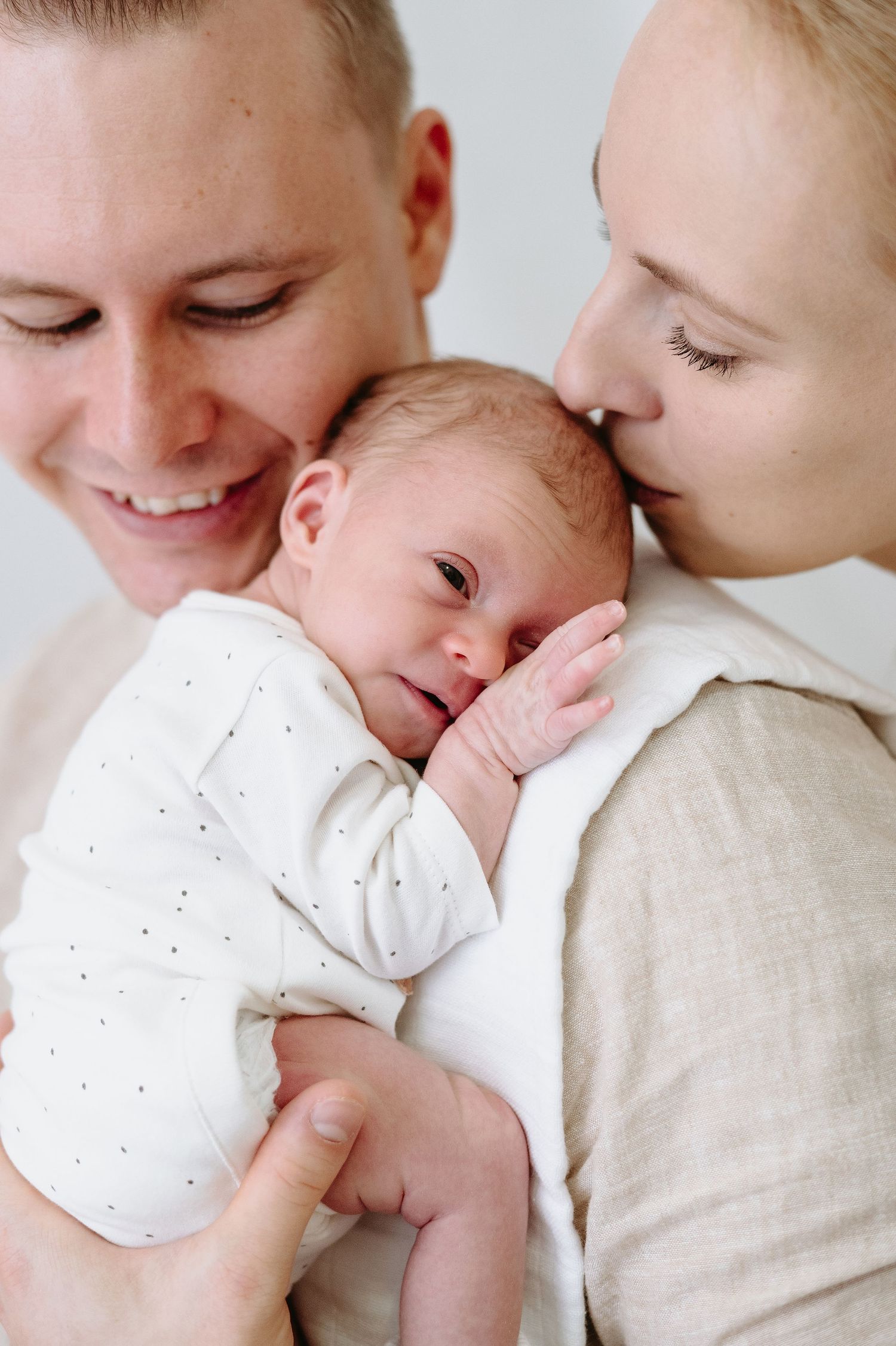 Close up portrait of newborn baby making expressive face while being held.