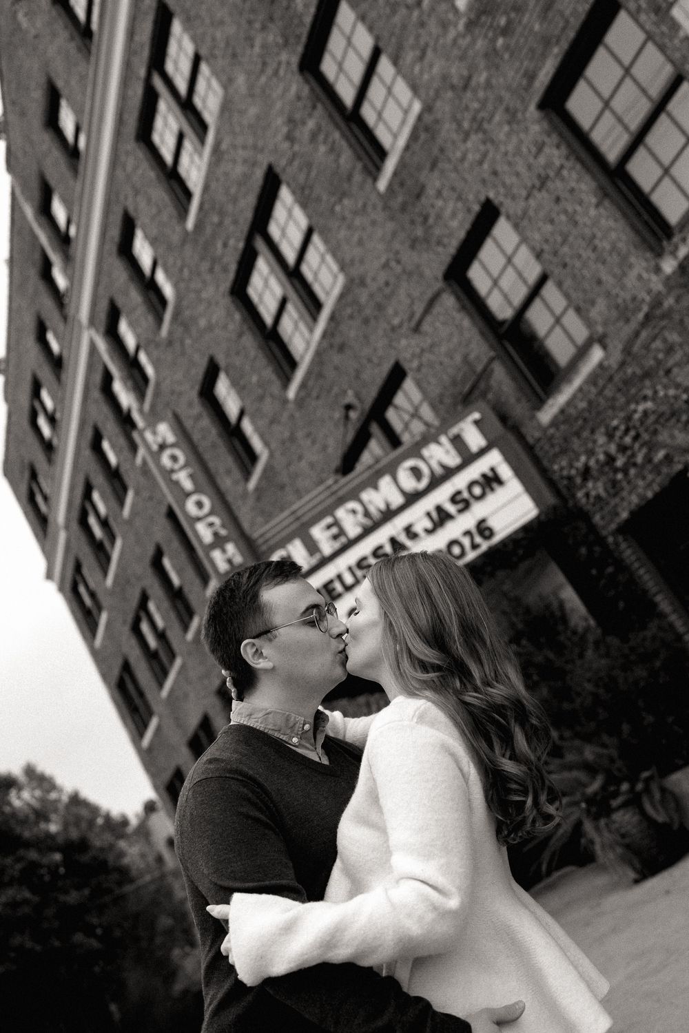 Couple kissing in black and white photo outside the historic Clermont Hotel marquee.