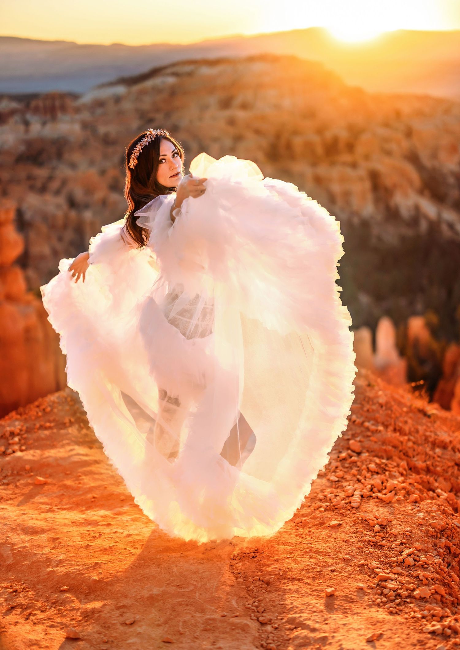 A ethereal figure in a flowing white dress poses dramatically against the red rock whodoos in Bryce Canyon