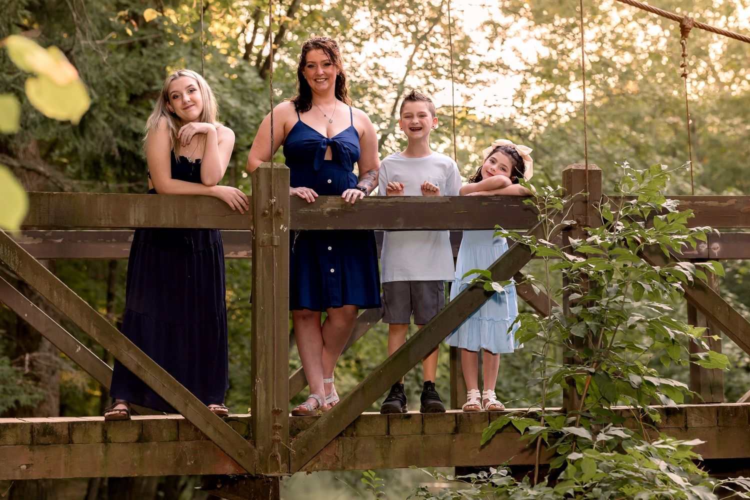 Family gathering on rustic wooden deck surrounded by lush greenery at sunset.