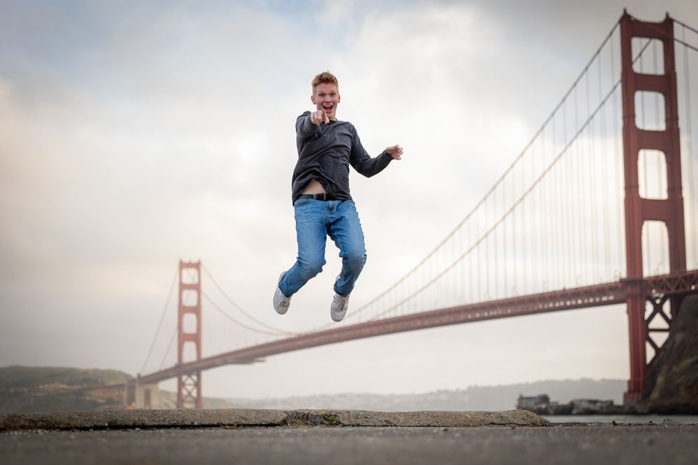 Person jumping mid-air with Golden Gate Bridge backdrop in San Francisco.