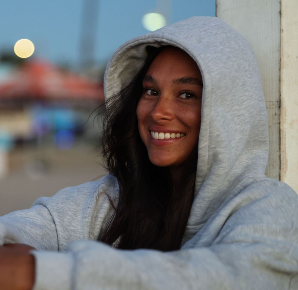 Someone wearing a light gray hooded sweatshirt is shown in a series of similar poses against a blurred background.