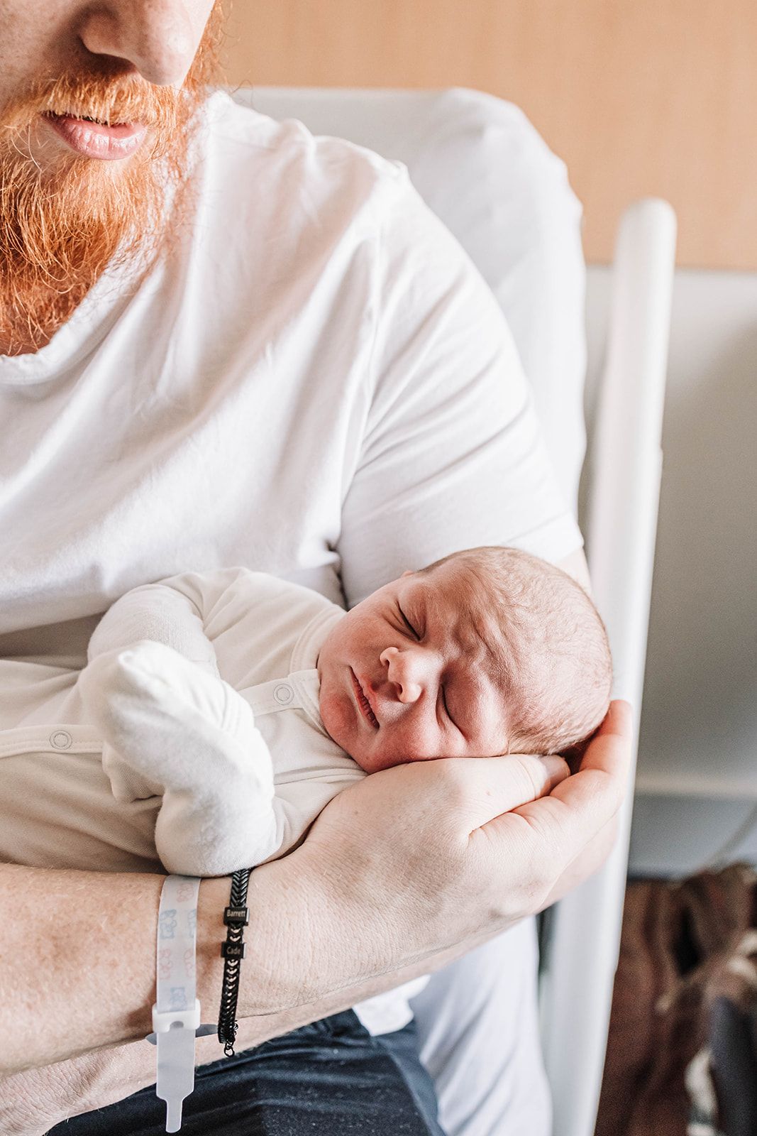 Photograph of a newborn held in the arms of his father at the hospital, a fresh 48 hours old, near Hershey PA in Dauphin County.