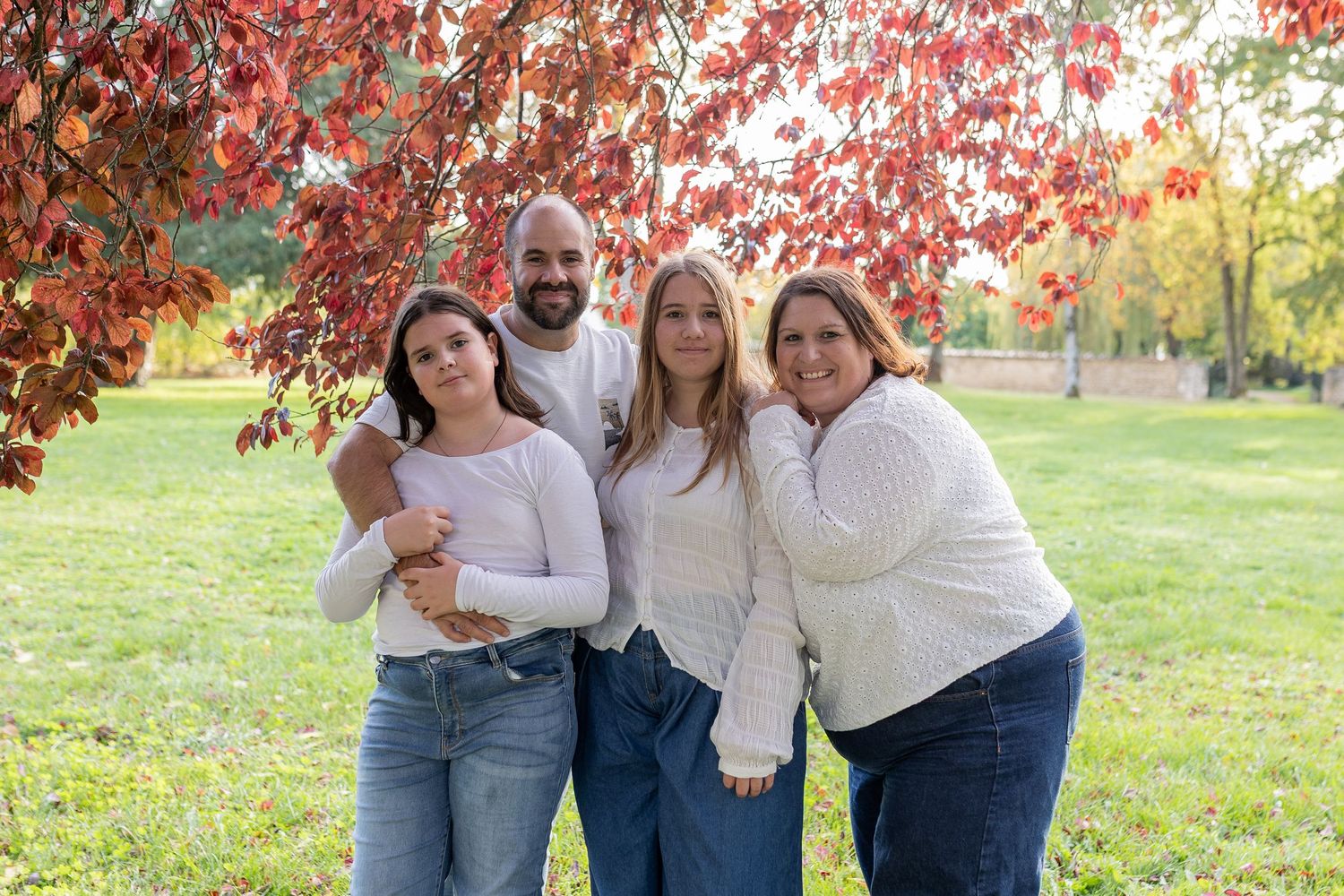 Portrait de famille avec deux enfants lors d'une séance photo en extérieur, parents et enfants complices en pleine nature en automne.