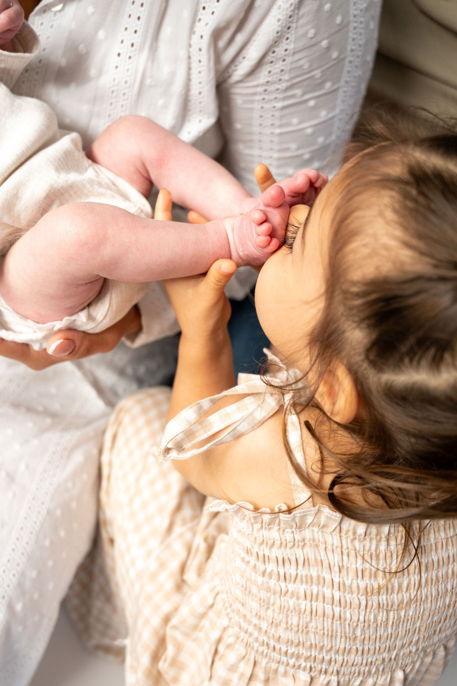 Detail shots of baby feet and hands against white eyelet fabric.