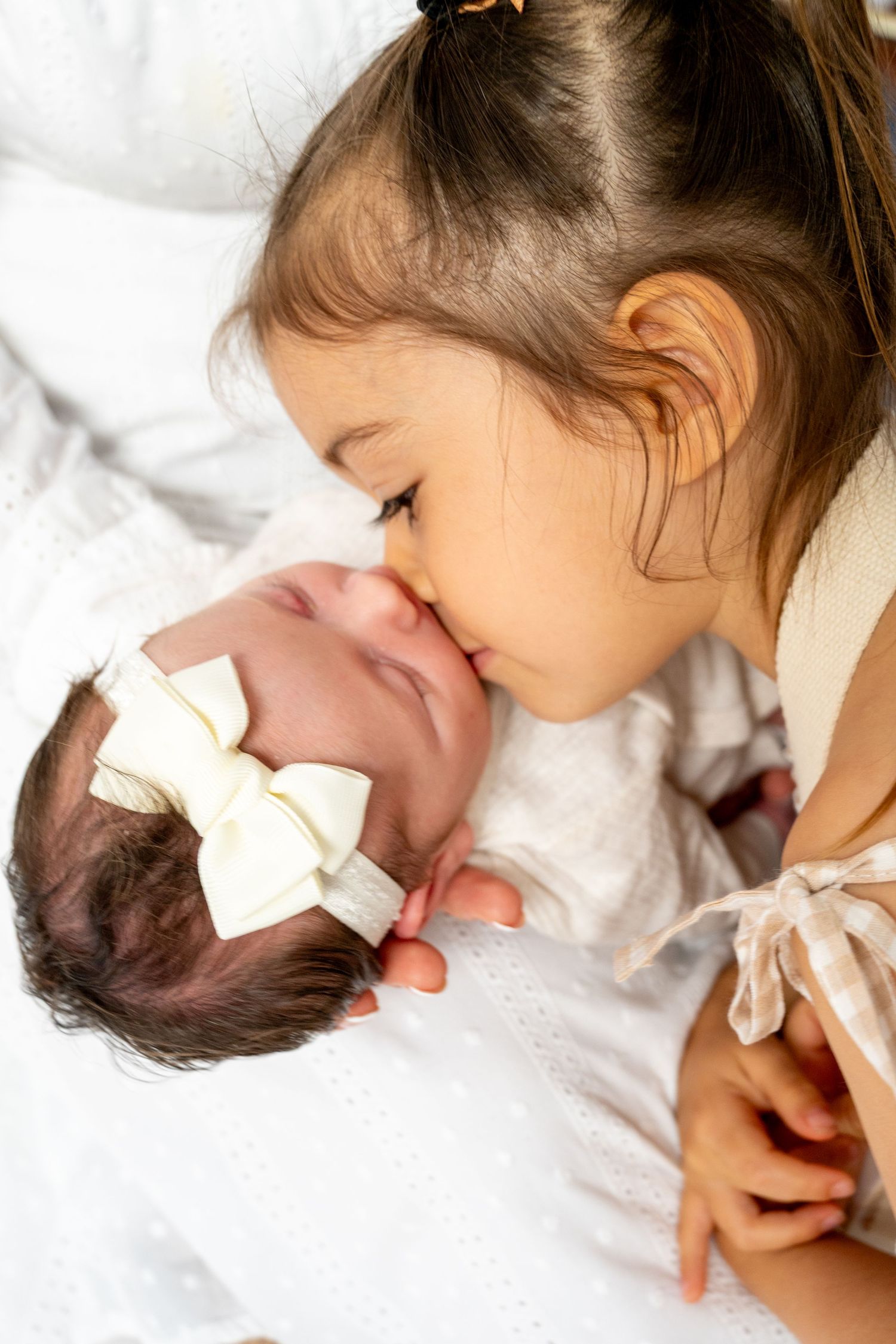 Intimate family moment with newborn baby on white bedding.