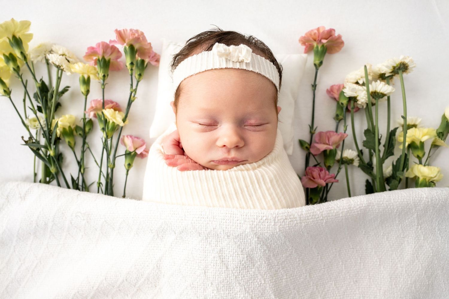 Floral backdrop with pink and yellow flowers arranged against a white background for a photo session.