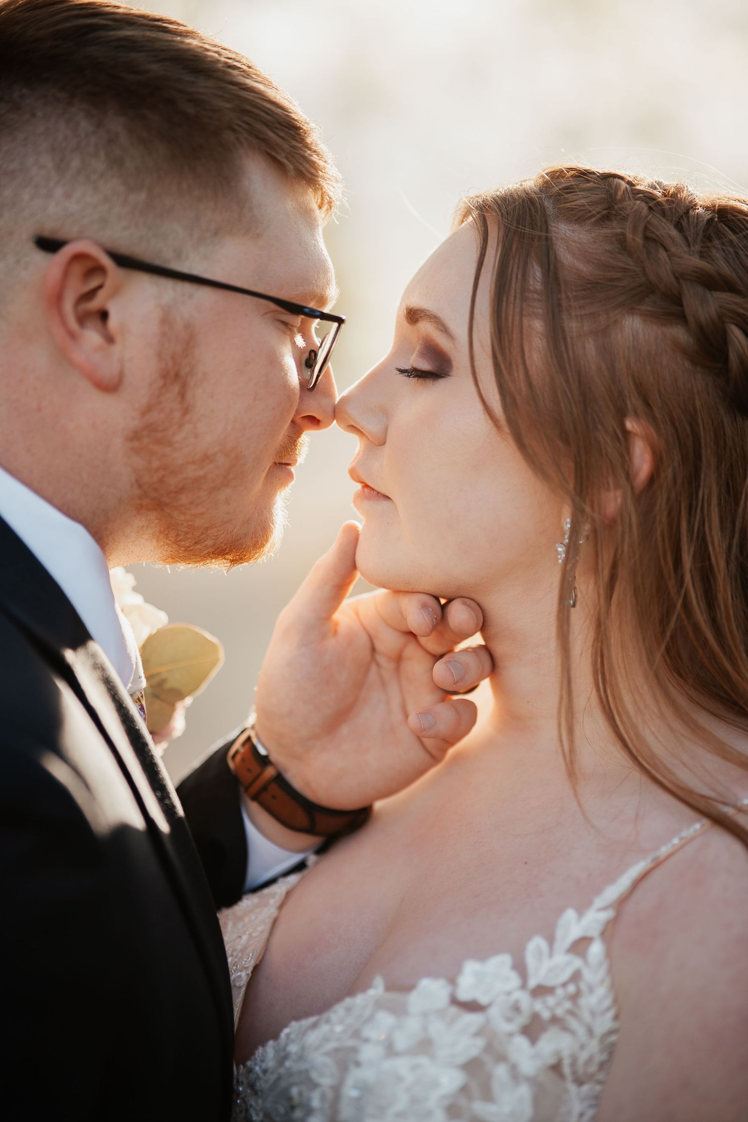 An intimate close-up portrait of newlyweds sharing a tender moment in golden light.