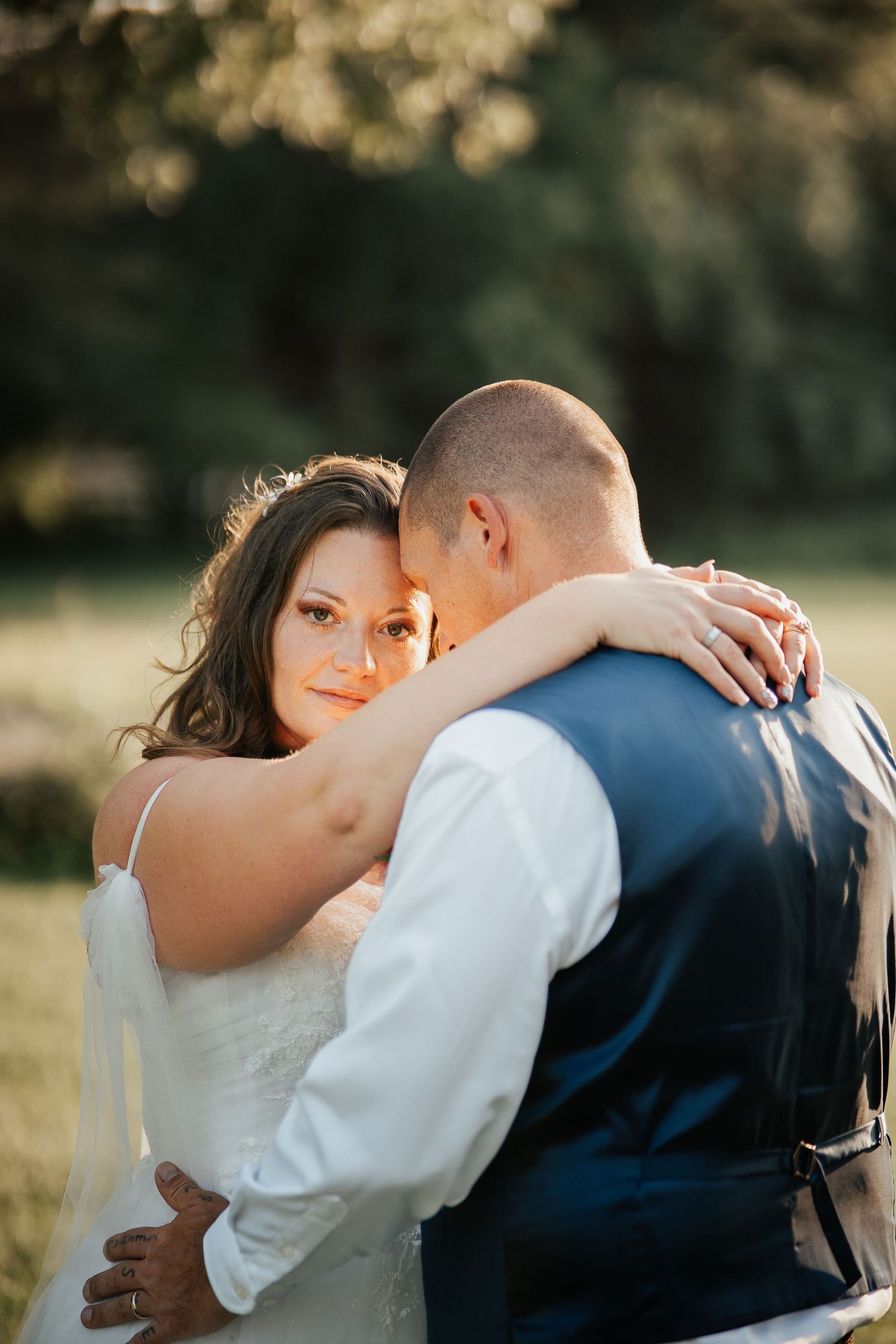 A tender embrace between newlyweds captured in warm evening sunlight.