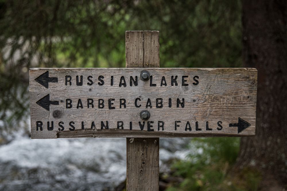 Weathered wooden directional sign points to Russian Lakes, Barber Cabin, and Russian River Falls.