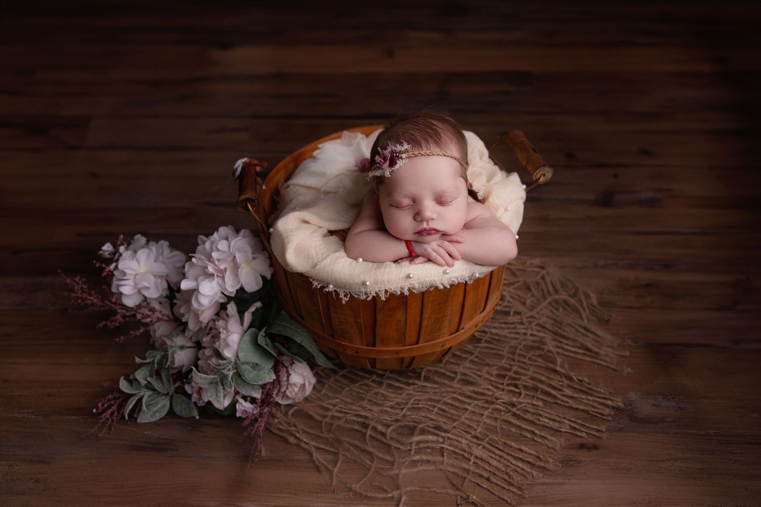 Newborn baby inside basket leaning head on hands